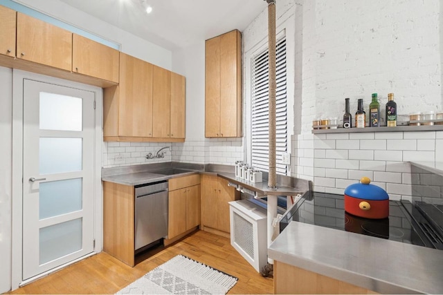 kitchen featuring sink, stainless steel counters, stainless steel dishwasher, light hardwood / wood-style floors, and backsplash