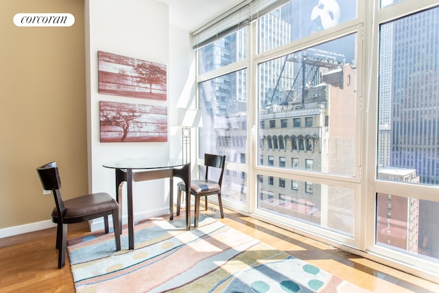 dining area with expansive windows, a city view, baseboards, and wood finished floors