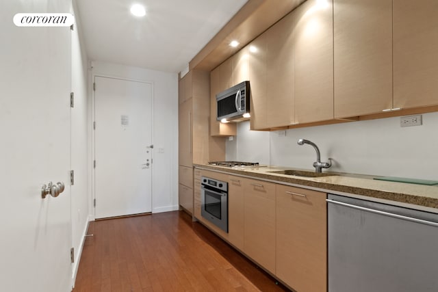 kitchen with visible vents, wood finished floors, light stone countertops, stainless steel appliances, and a sink