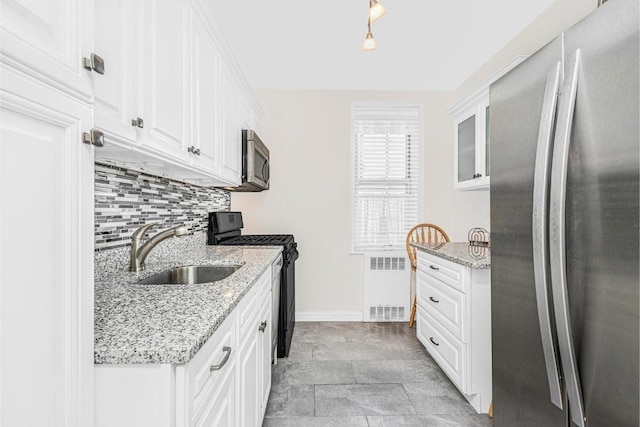 kitchen with appliances with stainless steel finishes, sink, white cabinetry, and radiator heating unit