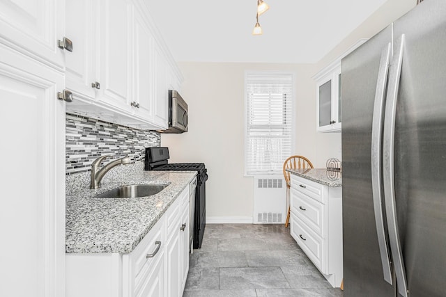 kitchen with white cabinets, a sink, radiator heating unit, stainless steel appliances, and baseboards