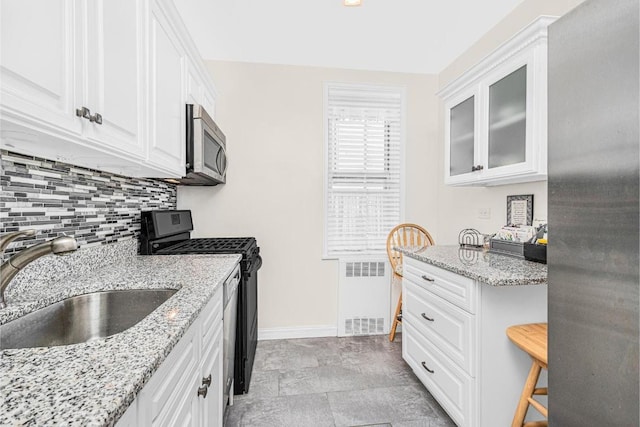 kitchen with sink, radiator, white cabinets, and black range with gas cooktop