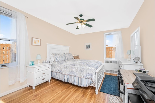 bedroom with a ceiling fan, baseboards, radiator heating unit, and light wood-style flooring
