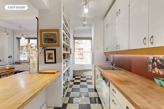 kitchen featuring butcher block counters, a sink, dark floors, and dishwashing machine