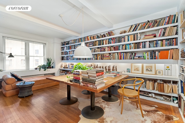 living area featuring beam ceiling, hardwood / wood-style floors, and bookshelves