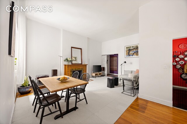 dining room featuring light wood-style floors, a brick fireplace, and baseboards