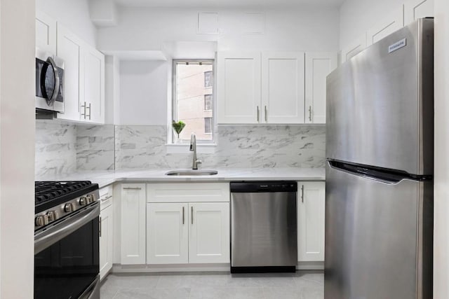 kitchen with sink, white cabinetry, stainless steel appliances, light tile patterned flooring, and decorative backsplash