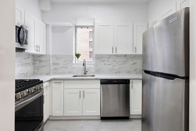 kitchen featuring stainless steel appliances, tasteful backsplash, a sink, and white cabinetry