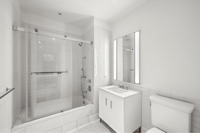 full bathroom featuring shower / bath combination with glass door, tile walls, vanity, tile patterned floors, and toilet