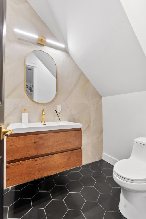 bathroom featuring tile patterned floors, vanity, toilet, and vaulted ceiling