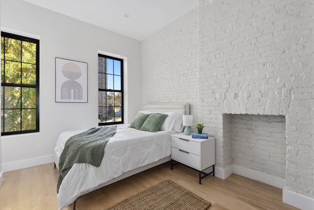 bedroom featuring light wood-type flooring and brick wall