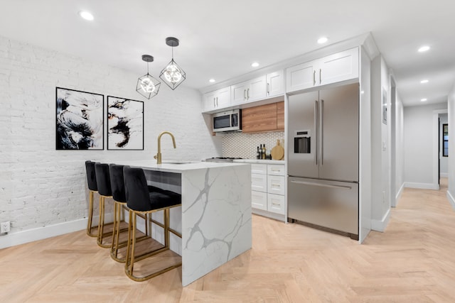 kitchen with appliances with stainless steel finishes, light parquet flooring, white cabinets, and sink