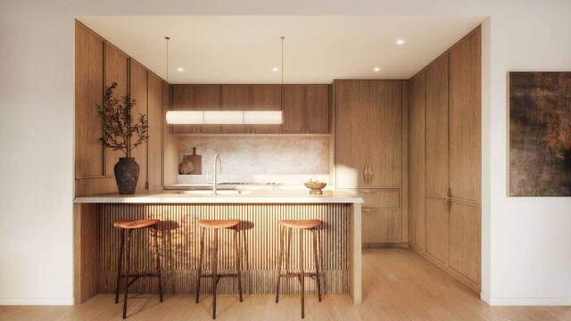 kitchen featuring light wood-type flooring, kitchen peninsula, sink, and a breakfast bar area