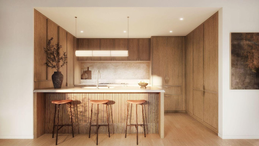 kitchen featuring light wood-type flooring, sink, a kitchen bar, and kitchen peninsula