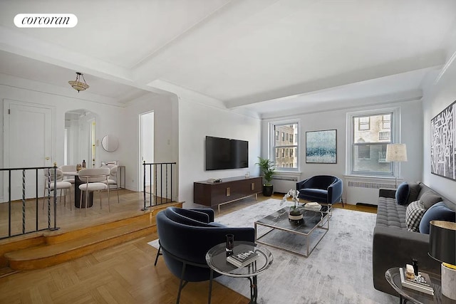 living room featuring visible vents, arched walkways, radiator, and beam ceiling