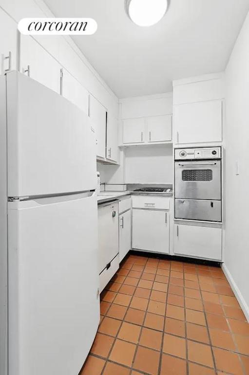 kitchen featuring dark tile patterned flooring, white cabinets, and stainless steel appliances