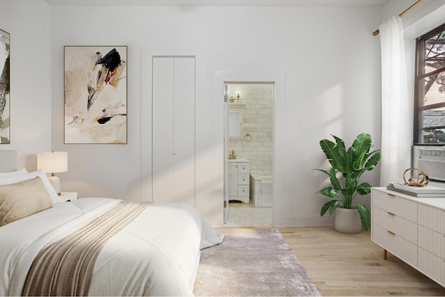 bedroom featuring light wood-type flooring and connected bathroom