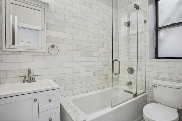 full bathroom with toilet, vanity, tile walls, and shower / bath combination with glass door