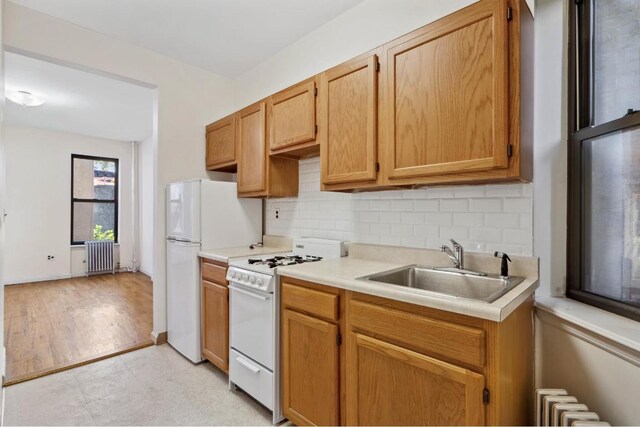 kitchen featuring gas range gas stove, decorative backsplash, sink, and radiator heating unit