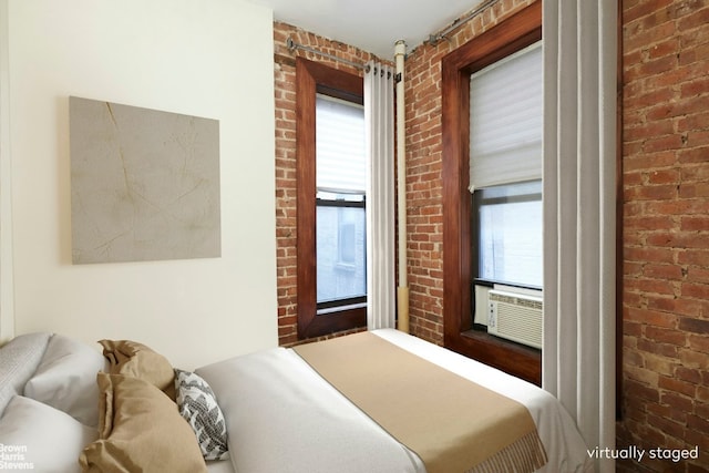 bedroom featuring cooling unit, brick wall, and multiple windows