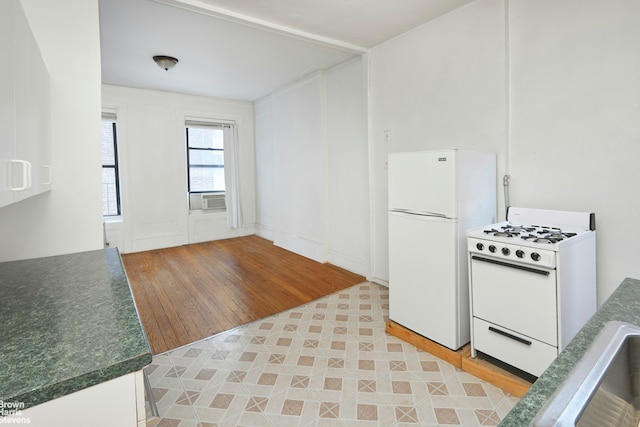 kitchen featuring white appliances, cooling unit, dark countertops, and light wood-type flooring