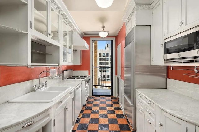 kitchen featuring wall chimney exhaust hood, sink, white cabinetry, premium appliances, and ornamental molding