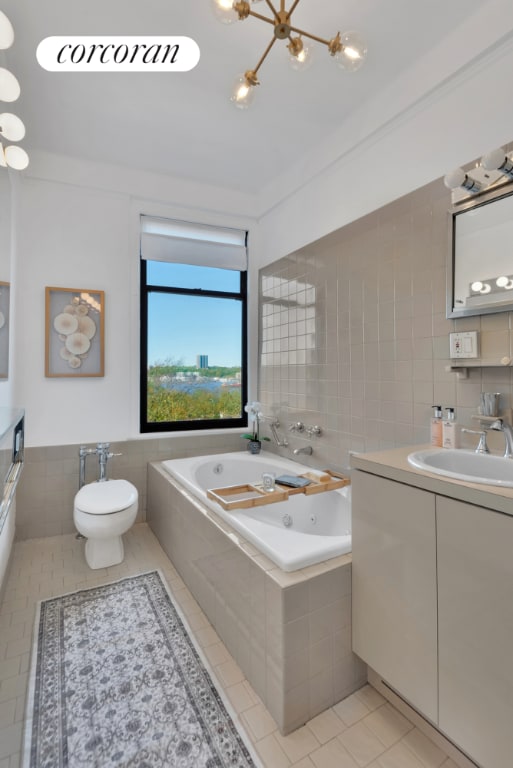 bathroom featuring toilet, vanity, tile walls, tile patterned floors, and tiled tub