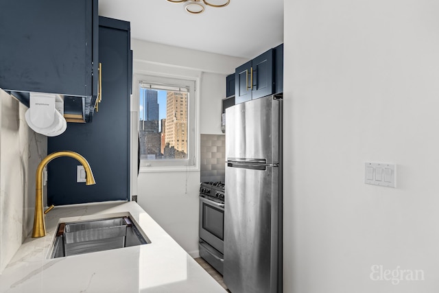 kitchen featuring appliances with stainless steel finishes, blue cabinets, a sink, light countertops, and backsplash