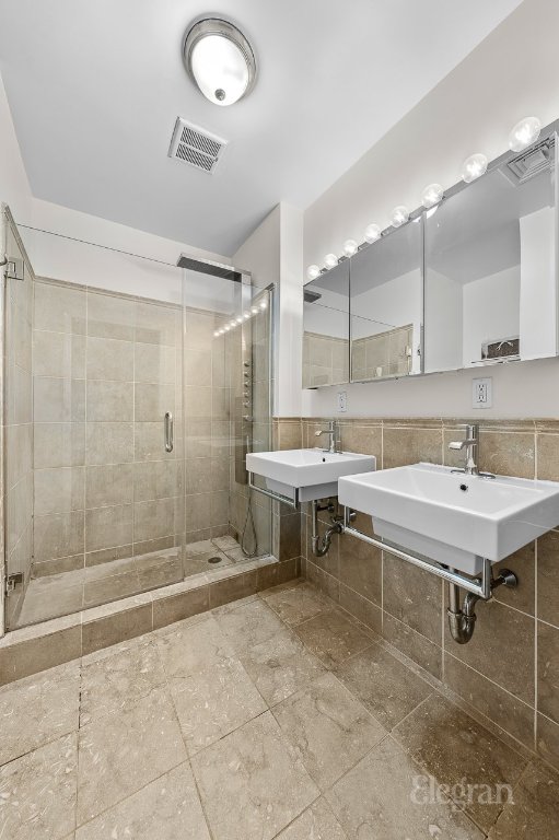 bathroom featuring tile walls, sink, and a shower with shower door