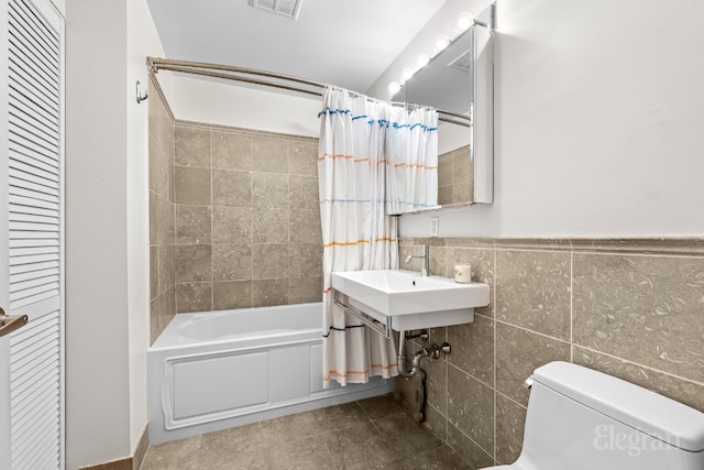 full bathroom featuring sink, toilet, shower / bath combination with curtain, and tile walls