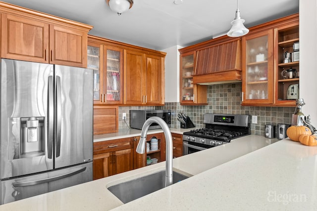 kitchen featuring brown cabinets, appliances with stainless steel finishes, premium range hood, and a sink