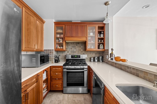 kitchen with decorative backsplash, appliances with stainless steel finishes, sink, and hanging light fixtures