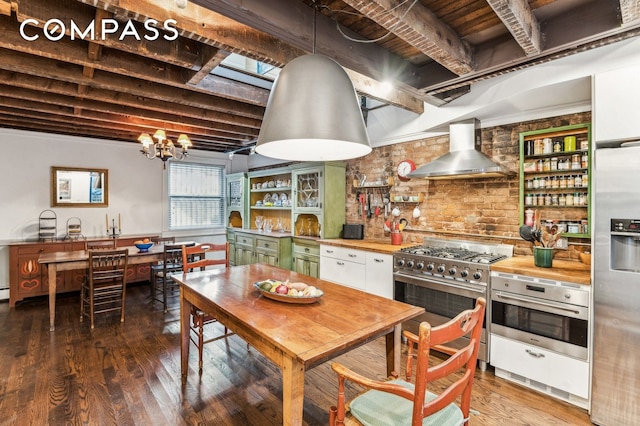 kitchen featuring wall chimney range hood, appliances with stainless steel finishes, dark wood-style floors, open shelves, and green cabinetry