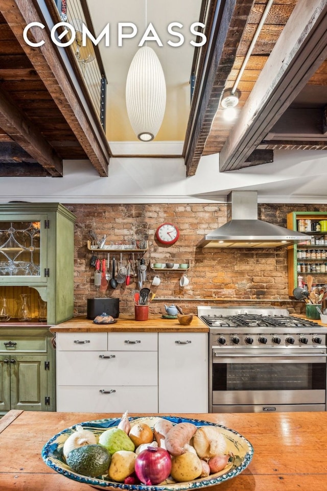 kitchen with green cabinets, butcher block countertops, high end stove, beamed ceiling, and wall chimney exhaust hood