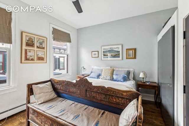 bedroom with dark wood-style floors, ceiling fan, and baseboard heating