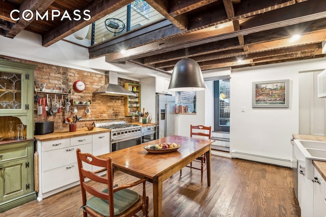 kitchen with a baseboard radiator, green cabinets, white cabinetry, high quality appliances, and wall chimney exhaust hood