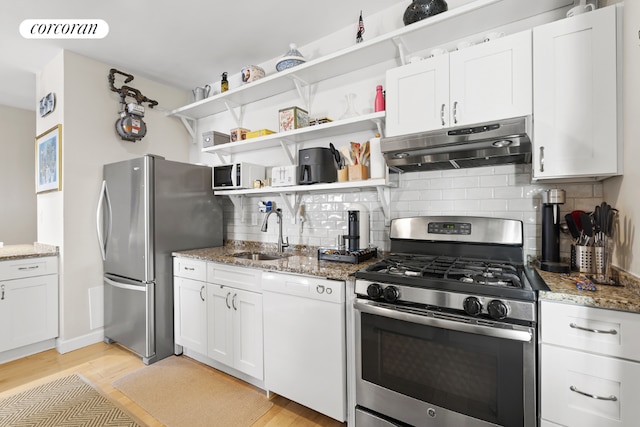 kitchen featuring sink, stainless steel appliances, white cabinetry, and dark stone counters