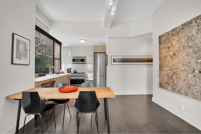 dining area with dark wood-style flooring, beam ceiling, and baseboards