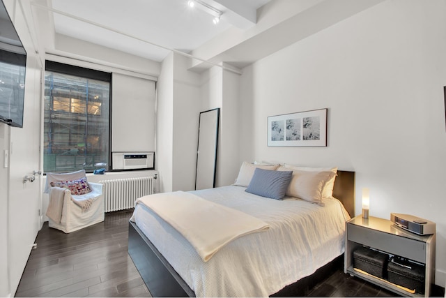 bedroom featuring dark wood-style floors, radiator heating unit, and rail lighting