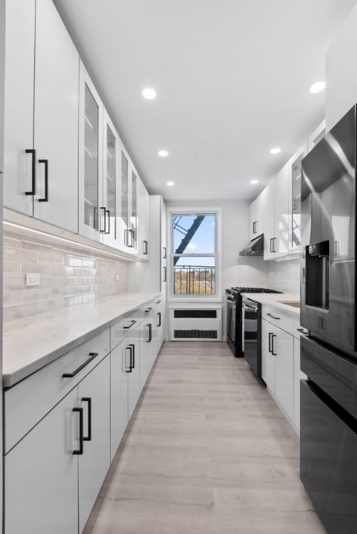 kitchen featuring stainless steel refrigerator with ice dispenser, backsplash, white cabinetry, and gas stove