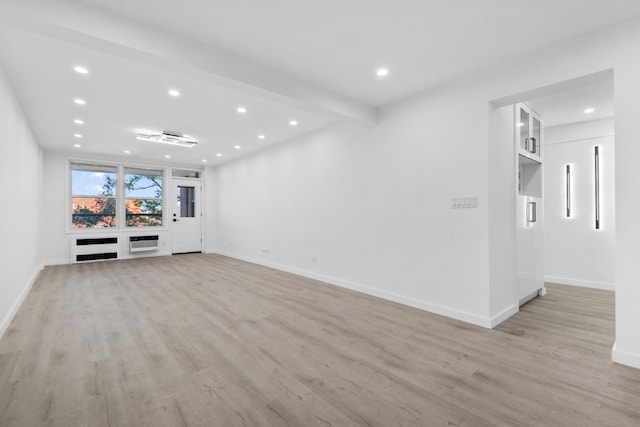 unfurnished living room with heating unit, beam ceiling, and light wood-type flooring