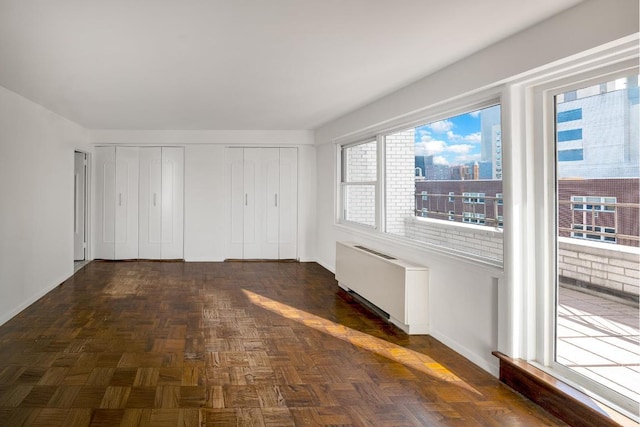 unfurnished bedroom featuring radiator and dark parquet flooring