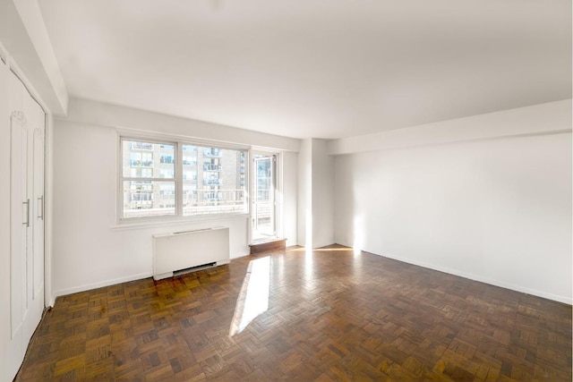 spare room featuring dark parquet flooring and radiator