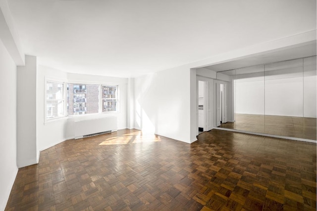 spare room with dark parquet flooring and radiator heating unit