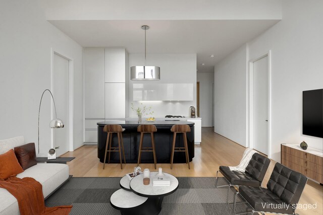 kitchen featuring white cabinetry, sink, hanging light fixtures, stainless steel appliances, and light wood-type flooring