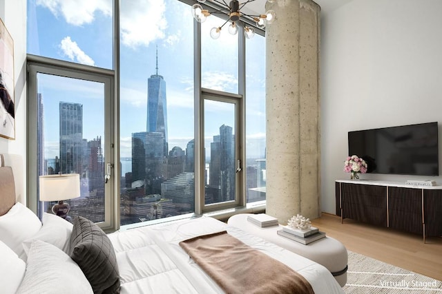 bedroom with a notable chandelier, light wood-type flooring, and a wall of windows