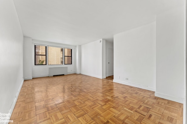 empty room with light parquet floors and radiator heating unit