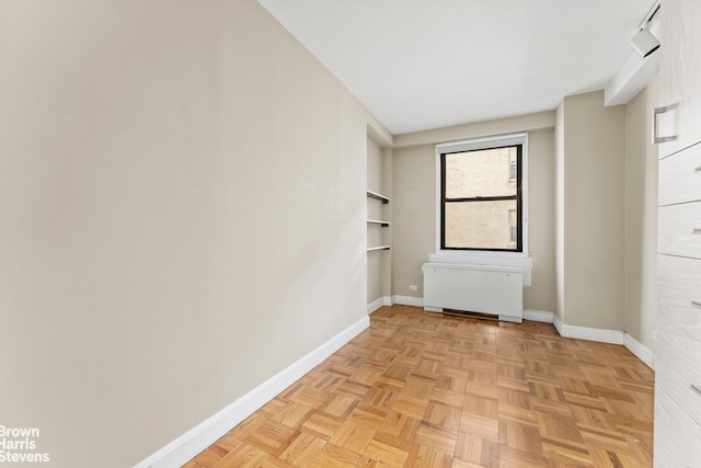 empty room with light parquet floors and radiator