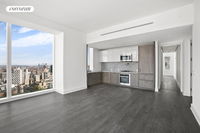 kitchen with appliances with stainless steel finishes, modern cabinets, dark wood finished floors, decorative backsplash, and baseboards