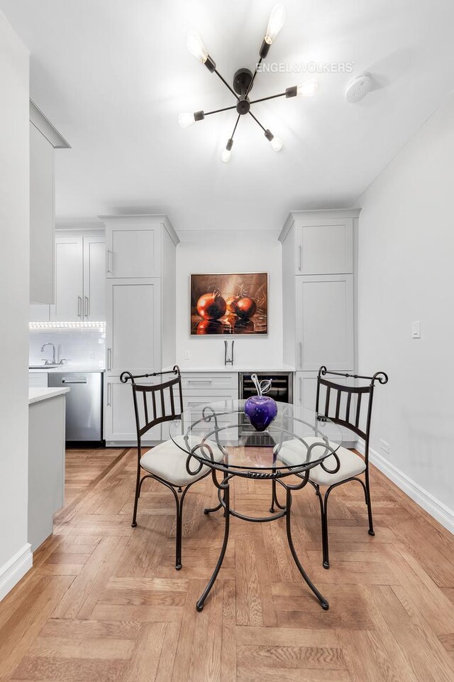 12 E 87th St Unit 8C, New York City, NY 10128 - dining space with baseboards, beverage cooler, and a notable chandelier